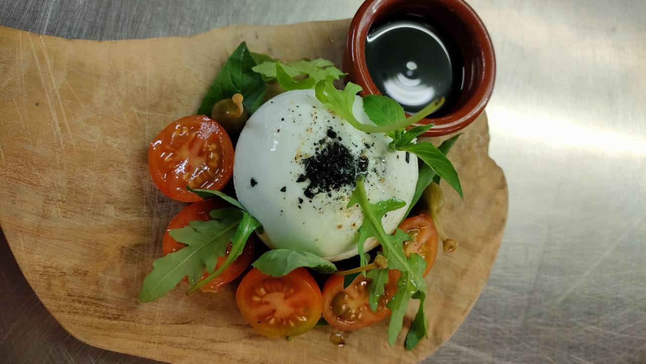 Burrata met tomaat en rucola op een houten plank