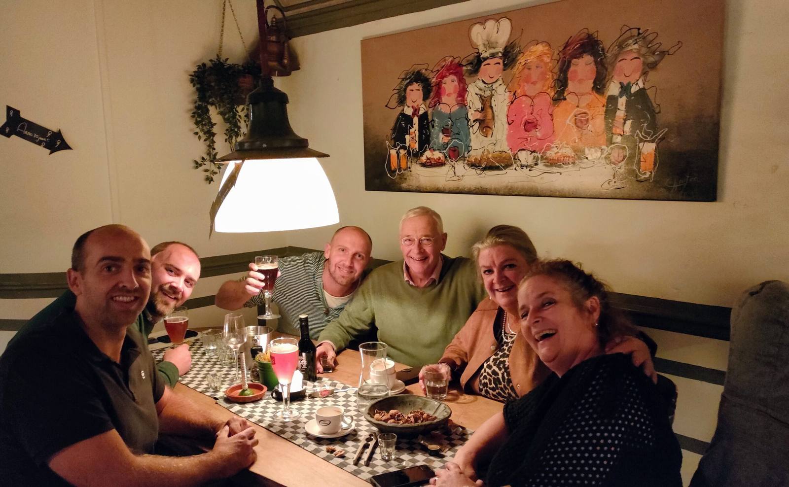 Een gezelschap aan tafel onder het schilderij