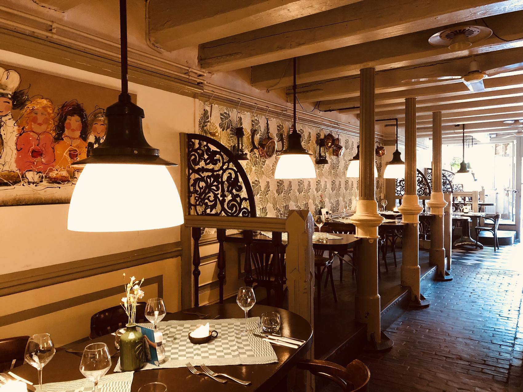 Het interieur van De Gaanderij met houten balken, lampen en gedekte tafels